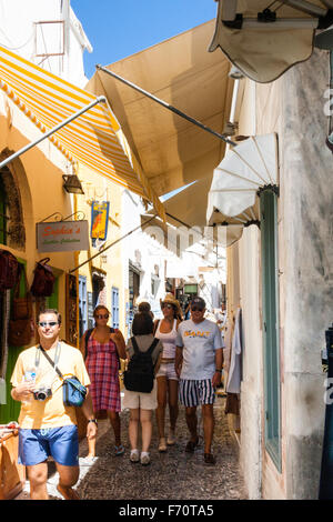 Santorini. Touristen zu Fuß durch die typischen engen gepflasterten Straße mit Geschäften auf beiden Seiten und Markisen Overhead, im alten Stadtzentrum von Fira entfernt. Stockfoto