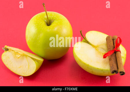 Frische Äpfel und Zimtstangen mit einem Band auf rotem Grund Stockfoto