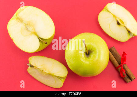 Frische Äpfel und Zimtstangen mit einem Band auf rotem Grund Stockfoto