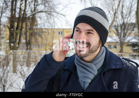 Bärtiger Mann reden über ein Handy im winter Stockfoto