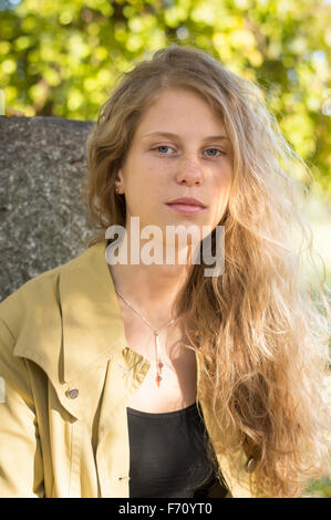 Porträt von einem schönen blonden Mädchen sitzt in einem park Stockfoto