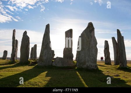 Blick nach Westen in den Mittelpunkt der (Calanais) Callanish Standing Stones prähistorische Monument. Isle of Lewis, Schottland; zwei Personen in der Silhouette. Stockfoto