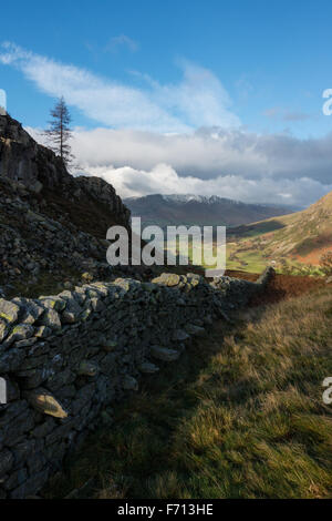 Eine Steinmauer liefen aus hohen Rigg in St. John's im Tal Tal mit Schnee bedeckt Blencathra in der Ferne. Stockfoto