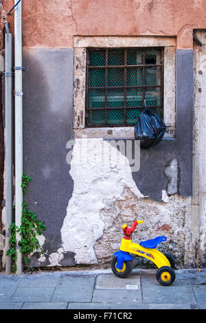 Venedig, Castello. Typischen venezianischen Haus außen mit Wasser beschädigt, Wand, Fenster, des Kindes Dreirad Stockfoto