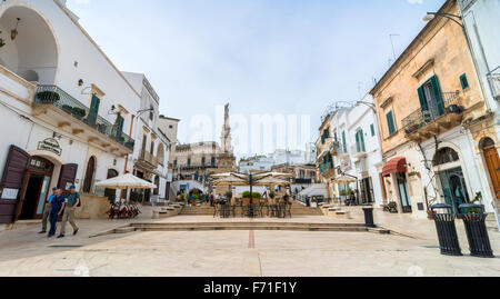 Touristen besuchen die Altstadt und die Statue des San Oronzo in Ostuni, Italien. Stockfoto