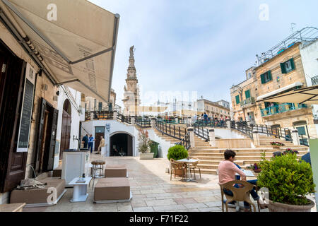 Touristen besuchen die Altstadt und die Statue des San Oronzo in Ostuni, Italien. Stockfoto