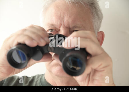 Ein älterer Mann hält ein altes Paar Ferngläser Stockfoto