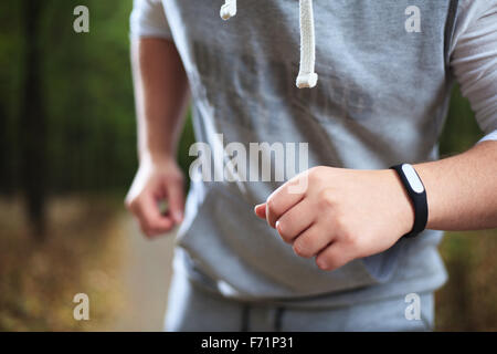 junger Mann mit Fitness-Armband während Morgenlauf Stockfoto