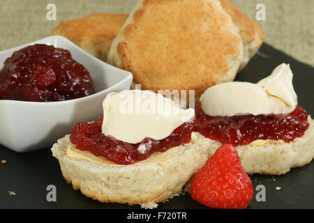 zwei halbiert home gebackene Scones mit Erdbeer-Marmelade und Sahne Stockfoto