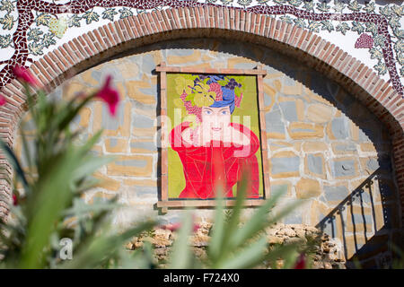 Ein Bild von einer Frau im roten Kleid gegen eine Wand in der Straße im Dorf von Manilva, Andalusien, Spanien. Stockfoto