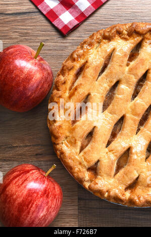 Hohen Winkel Detailansicht ein frisch gebackenen Apfelkuchen mit Äpfeln auf einem rustikalen Holztisch. Hochformat. Stockfoto