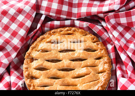 Nahaufnahme von einem frischen gebackenen Apfelkuchen, umgeben von einer roten und weißen aufgegebenes Tischdecke. Stockfoto