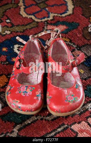 Ein gut getragen paar kleinen Mädchens leuchtend rotem Lederschuhe auf einen Teppich gelegt. Stockfoto