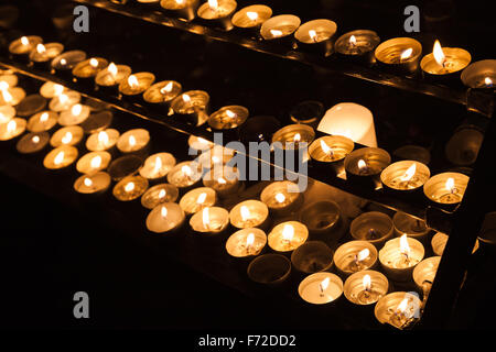 Große Gruppe von kleinen Kerzen brennen in den Regalen in dunklen katholische Kirche Stockfoto