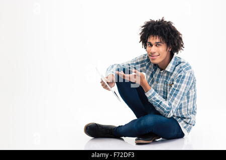 Porträt von Afro amerikanische glücklich auf dem Boden sitzend mit Tablet-Computer auf einem weißen Hintergrund isoliert Stockfoto