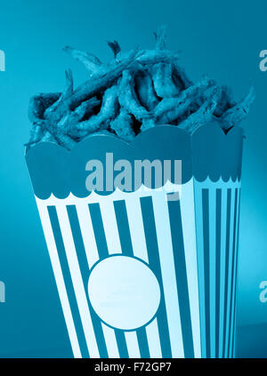 Ironische Bild der Karton mit gebratenen Fisch stattdessen Popcorn Kopie Raum Blau Ton Stockfoto