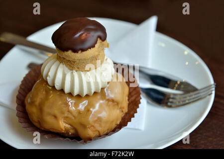 Eclair Kuchen garniert mit Schokoladensauce und Schlagsahne in natürlichem Licht fotografiert Stockfoto