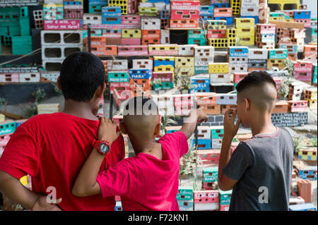 RIO DE JANEIRO, Brasilien - 16. Oktober 2015: Junge Brasilianer stehen und blicken auf eine soziale Kunst-Installation-Darstellung einer Favela. Stockfoto