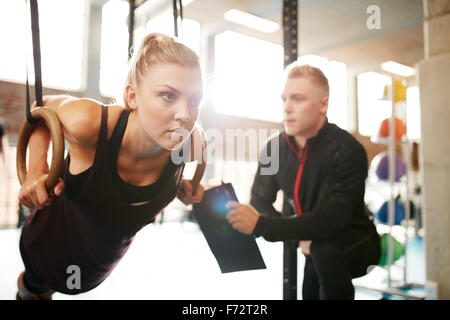 Fit junge Frau mit ihrem persönlichen Fitness-Trainer im Fitness-Studio trainieren mit Gymnastik Ringen Stockfoto