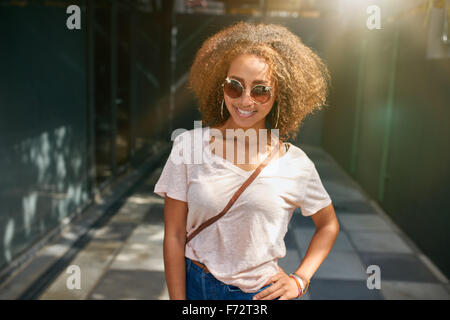 Porträt von einer attraktiven jungen Frau posiert mit der Hand auf die Hüfte. Schöne afrikanische Frau in stilvollen Casuals posiert im Freien. Stockfoto