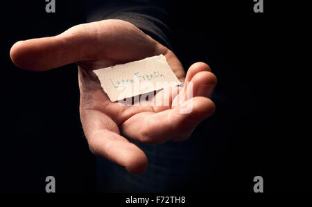 Ein Mann hält eine Karte mit einer Hand schriftliche Nachricht, Französisch lernen. Stockfoto
