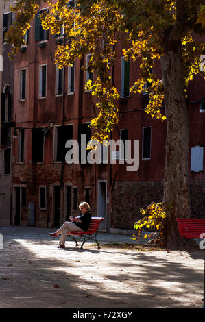 Campo San Agnese in Sestiere di Dorsoduro in Venedig. Eine Frau eine Frau, die im Herbst lesen. Stockfoto