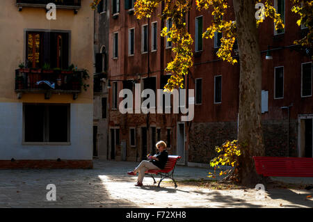 Campo San Agnese in Sestiere di Dorsoduro in Venedig. Eine Frau eine Frau, die im Herbst lesen. Stockfoto