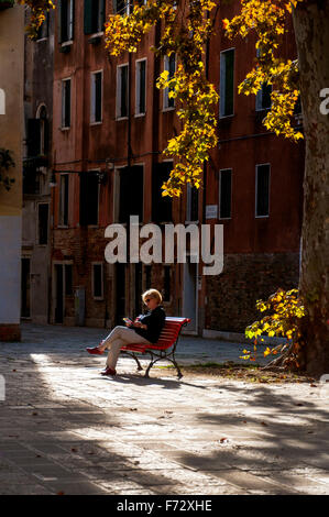 Campo San Agnese in Sestiere di Dorsoduro in Venedig. Eine Frau eine Frau, die im Herbst lesen. Stockfoto