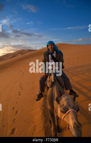 Ein Tourist der Kamelritt und bewundern Sie den Sonnenuntergang von einem Hügel aus. Einige Schleifen Hügel am Erg Chebbi in der Wüste Sahara.  Ers sind groß Stockfoto