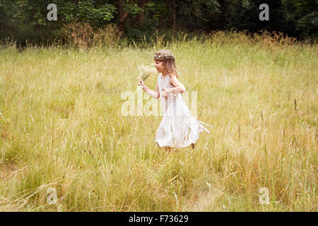 Junges Mädchen mit Blumen im Haar Kommissionierung Wildblumen auf einer Wiese. Stockfoto