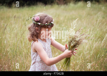 Junges Mädchen mit Blumen im Haar Kommissionierung Wildblumen auf einer Wiese. Stockfoto