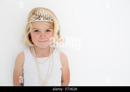 Junges Mädchen trägt eine Tiara und eine Perlenkette für ein Bild in einem Studio des Fotografen zu posieren. Stockfoto