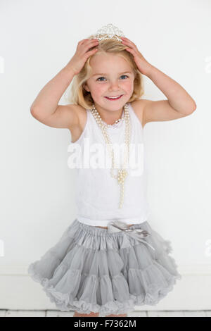 Junges Mädchen trägt eine Tiara und eine Perlenkette für ein Bild in einem Studio des Fotografen zu posieren. Stockfoto