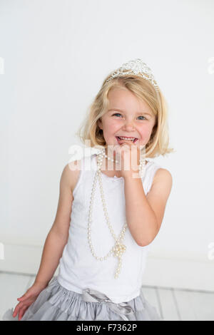 Junges Mädchen trägt eine Tiara und eine Perlenkette für ein Bild in einem Studio des Fotografen zu posieren. Stockfoto