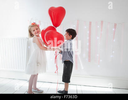 Jungen und Mädchen posieren für ein Foto in einem Studio Fotografen halten rote Luftballons. Stockfoto
