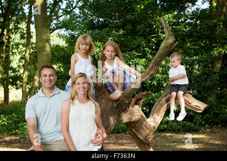 Familie mit drei Kindern von einem Baum in einem Wald, posiert für ein Foto. Stockfoto