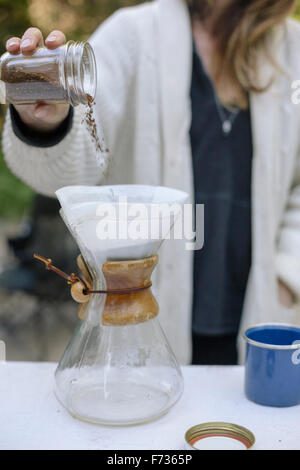 Frau, Gießen gemahlenen Kaffee aus dem Glas in ein Glas-Kaffeemaschine. Stockfoto