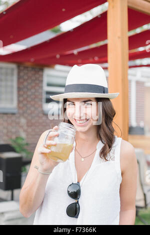 Lächelnde Frau in einem Garten stehen, einen Drink zu halten. Stockfoto