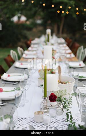 Langer Tisch set mit Teller und Gläser, Essen und trinken in einem Garten. Stockfoto