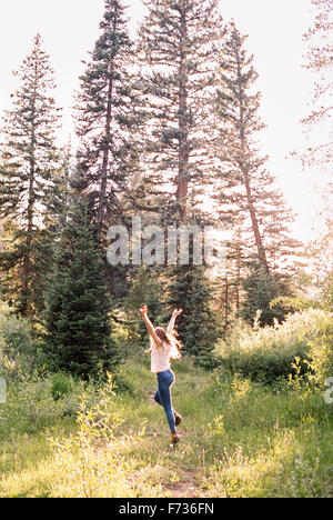 Frau mit Freude in einem sonnendurchfluteten Wald springen. Stockfoto