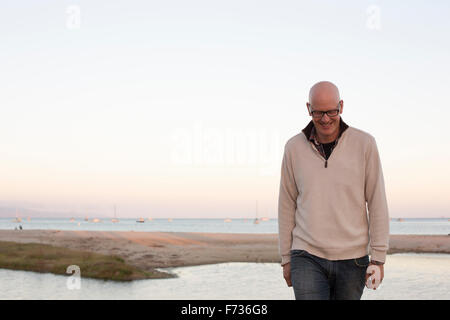 Glatze Mann zu Fuß auf einen Sandstrand am Meer. Stockfoto