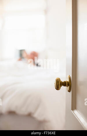 Mann liegt im Bett mit weißem Leinen, lesen. Stockfoto