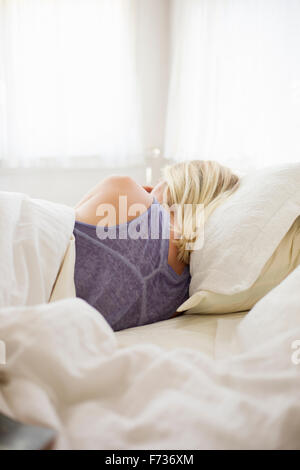 Blonde Frau schläft in einem Bett mit weißem Leinen. Stockfoto