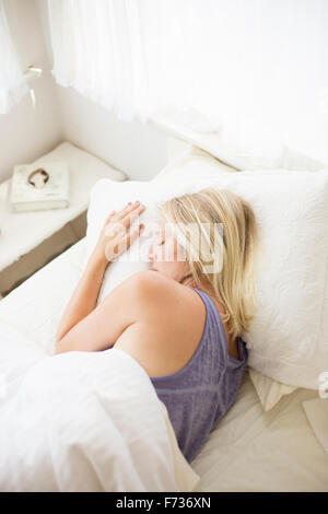 Blonde Frau schläft in einem Bett mit weißem Leinen. Stockfoto