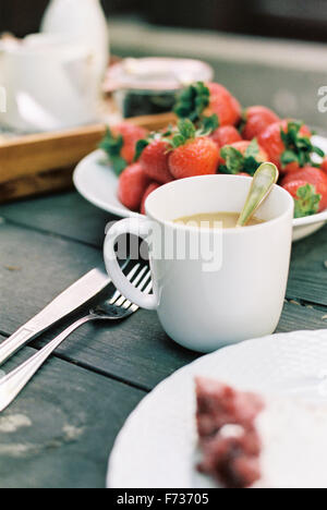 Tasse Tee und Teller mit frischen Erdbeeren auf einem Tisch. Stockfoto