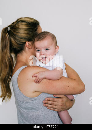 Eine Frau wiegt ein Kind, ein Mädchen auf ihrer Schulter hält. Stockfoto