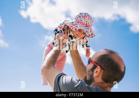 Ein Baby liegend auf einem Schaffell-Teppich, ihre Beine zu treten. Stockfoto