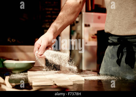 Bäcker arbeiten auf einer bemehlten Fläche teilen vorbereitet Teig in Quadrate. Stockfoto