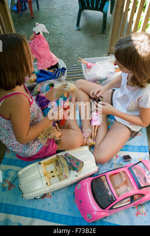 Zwei junge Mädchen spielen mit Barbie-Puppen auf Veranda Stockfoto