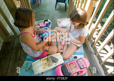 Zwei junge Mädchen spielen mit Barbie-Puppen auf Veranda Stockfoto